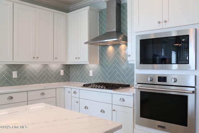 3347 Island Lakes Dr, Oak Island, NC 28461 - kitchen with white cabinets, wall chimney range hood, crown molding, and stainless steel appliances