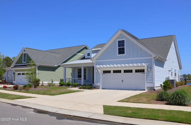 3347 Island Lakes Dr, Oak Island, NC 28461 - craftsman inspired home featuring driveway, board and batten siding, a shingled roof, a porch, and a garage