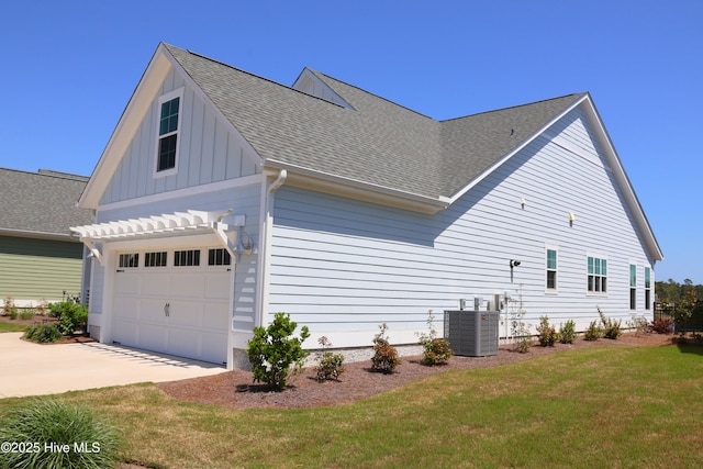 3347 Island Lakes Dr, Oak Island, NC 28461 - view of property exterior with central air condition unit, concrete driveway, board and batten siding, a lawn, and a garage