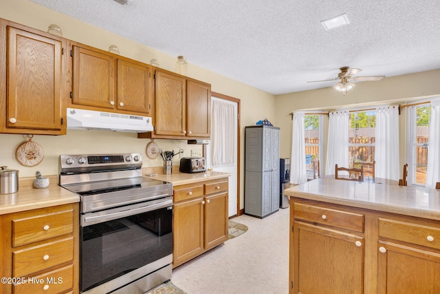 3421 Bethel Rd, Wilmington, NC 28409 - kitchen with under cabinet range hood, light countertops, a ceiling fan, stainless steel electric stove, and a textured ceiling