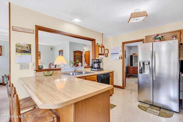 3421 Bethel Rd, Wilmington, NC 28409 - kitchen featuring a breakfast bar, a sink, a peninsula, stainless steel fridge, and a textured ceiling