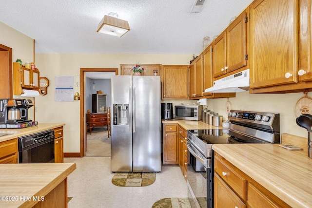 3421 Bethel Rd, Wilmington, NC 28409 - kitchen featuring stainless steel appliances, light countertops, under cabinet range hood, and brown cabinets