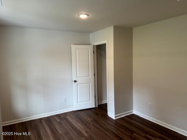 unfurnished bedroom with dark wood finished floors and baseboards