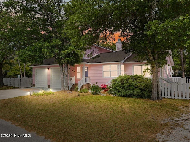 7501 E Oak Island Dr, Oak Island, NC 28465 - view of front of home featuring driveway, fence, a chimney, and a yard