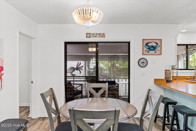 7501 E Oak Island Dr, Oak Island, NC 28465 - dining room with an inviting chandelier, a textured ceiling, wood finished floors, and baseboards