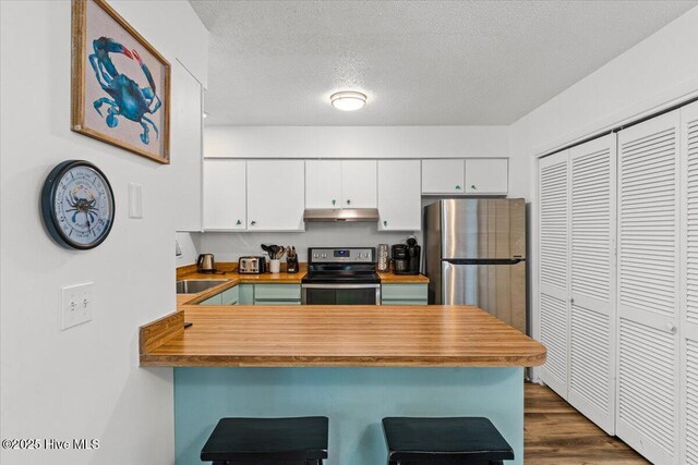 7501 E Oak Island Dr, Oak Island, NC 28465 - kitchen with stainless steel appliances, white cabinets, a peninsula, and under cabinet range hood