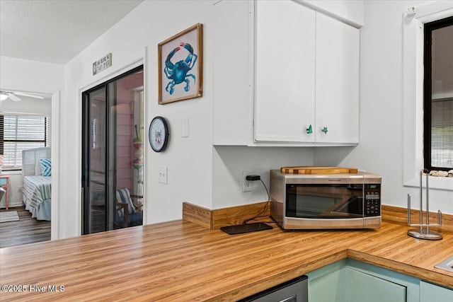 7501 E Oak Island Dr, Oak Island, NC 28465 - room details featuring white cabinets, ceiling fan, butcher block countertops, and stainless steel microwave