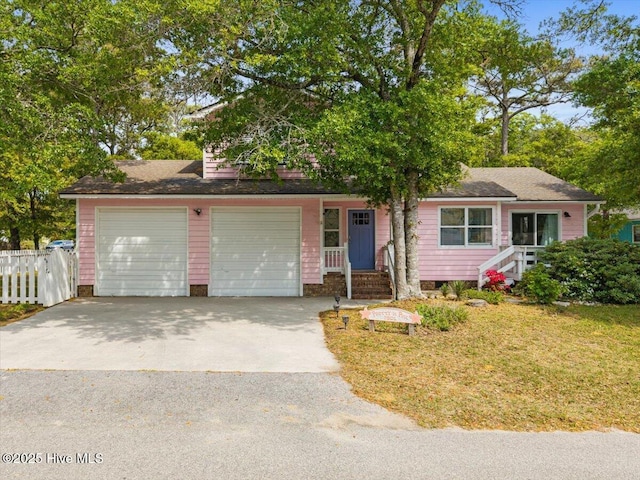 7501 E Oak Island Dr, Oak Island, NC 28465 - view of front of home with a front lawn, driveway, roof with shingles, an attached garage, and fence