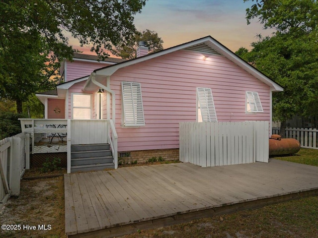 7501 E Oak Island Dr, Oak Island, NC 28465 - view of property exterior featuring a deck, fence, and a chimney