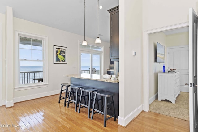 1113 Ocean Dr, Emerald Isle, NC 28594 - kitchen with baseboards, a kitchen bar, a healthy amount of sunlight, and light wood-style floors