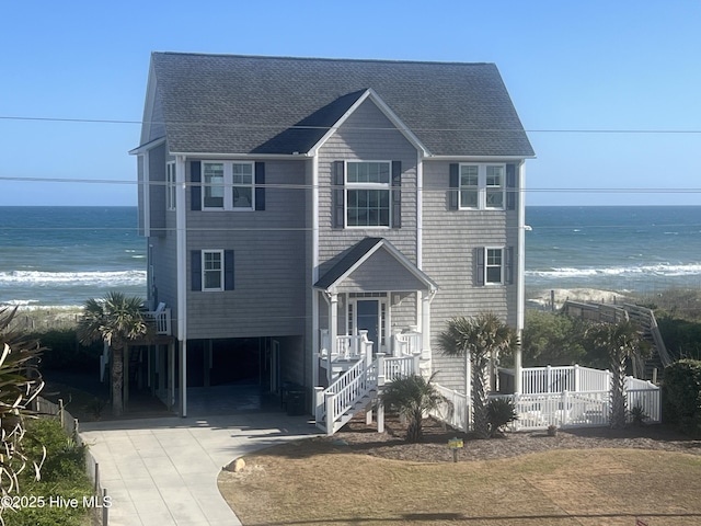 1113 Ocean Dr, Emerald Isle, NC 28594 - raised beach house with concrete driveway, a water view, fence, and roof with shingles