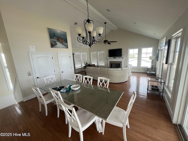 1113 Ocean Dr, Emerald Isle, NC 28594 - dining area with a fireplace, dark wood-type flooring, baseboards, high vaulted ceiling, and a chandelier