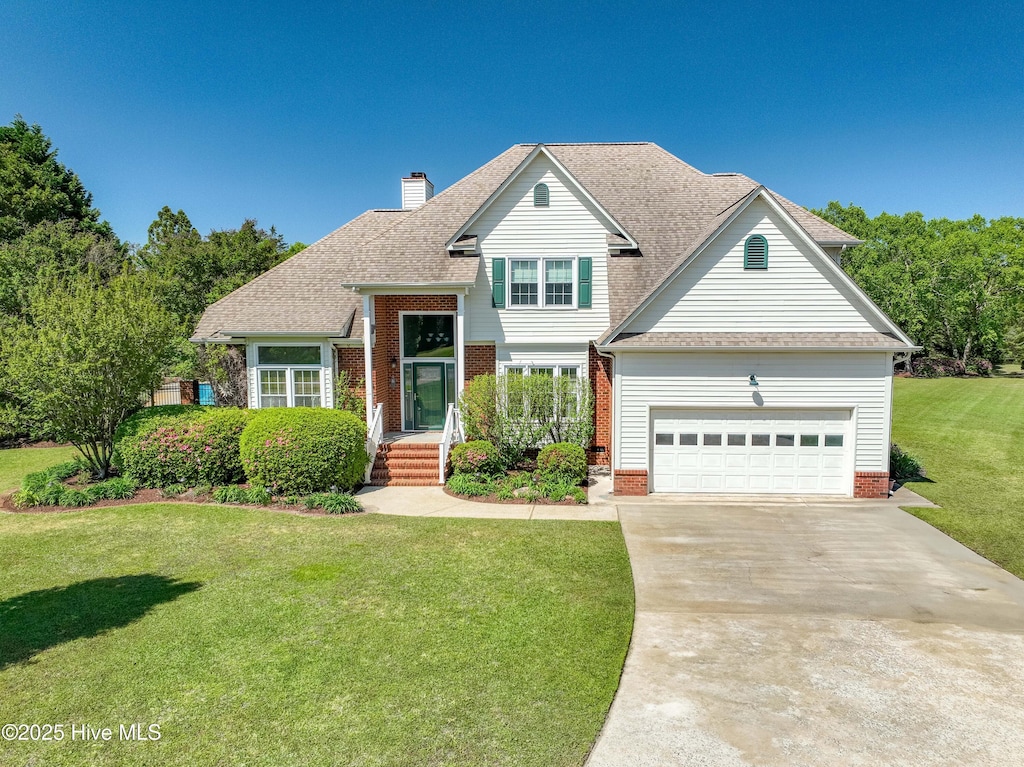 view of front of property with driveway, a chimney, an attached garage, a shingled roof, and a front yard