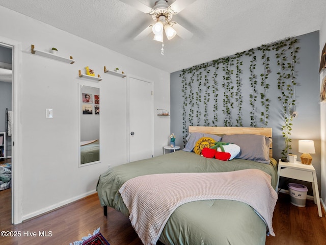 bedroom with wood finished floors, a textured ceiling, baseboards, and ceiling fan