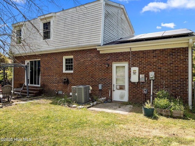 back of house featuring central AC, brick siding, a yard, and entry steps