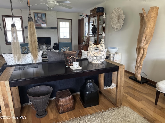living room with wood finished floors, a ceiling fan, baseboards, and a fireplace