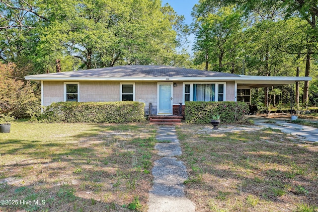 ranch-style house with concrete block siding, a shingled roof, a front lawn, and an attached carport