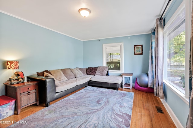 living room with wood finished floors, visible vents, crown molding, and baseboards