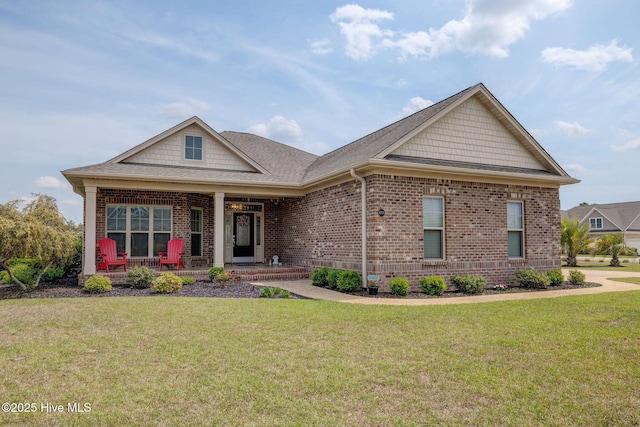 craftsman-style house featuring a front lawn, brick siding, a shingled roof, and covered porch