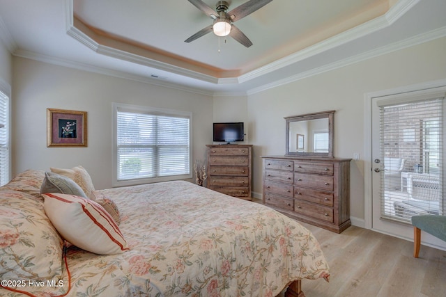 bedroom featuring a raised ceiling, light wood-style floors, crown molding, and access to outside