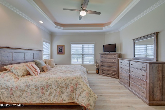 bedroom with light wood-type flooring, ceiling fan, a raised ceiling, and crown molding