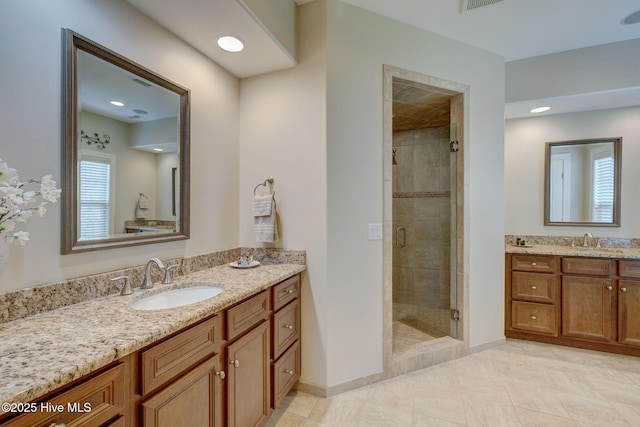 bathroom featuring two vanities, baseboards, a sink, and a stall shower