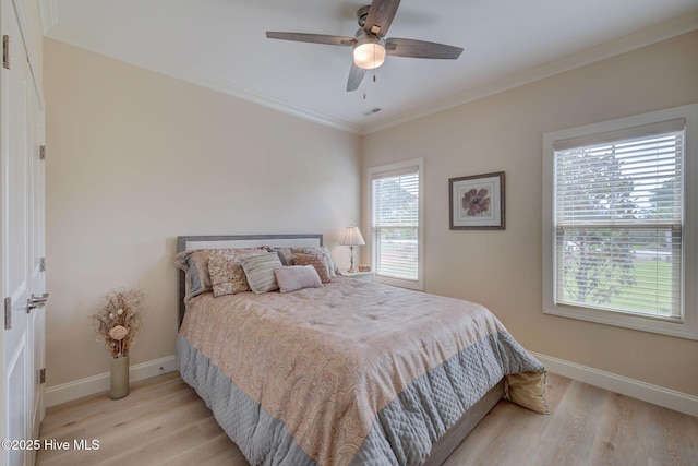 bedroom with a ceiling fan, light wood-style flooring, baseboards, ornamental molding, and visible vents