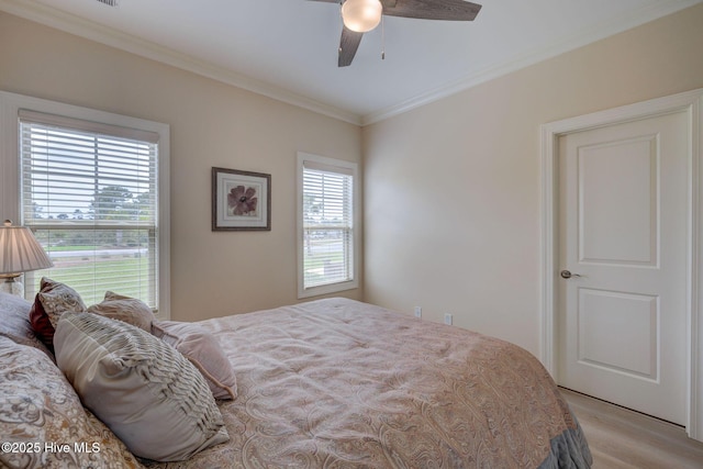 bedroom featuring light wood-style flooring, crown molding, and ceiling fan