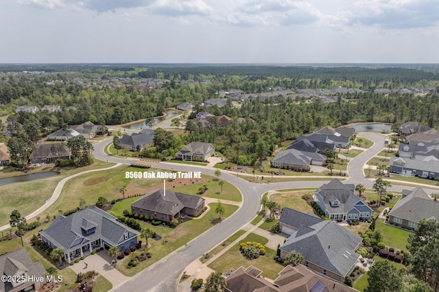 drone / aerial view with a wooded view, a residential view, and a water view