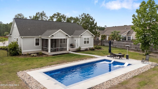 back of house with a sunroom, a patio area, a shingled roof, and board and batten siding
