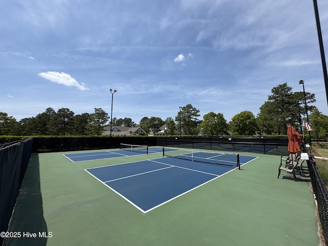 view of tennis court with community basketball court and fence