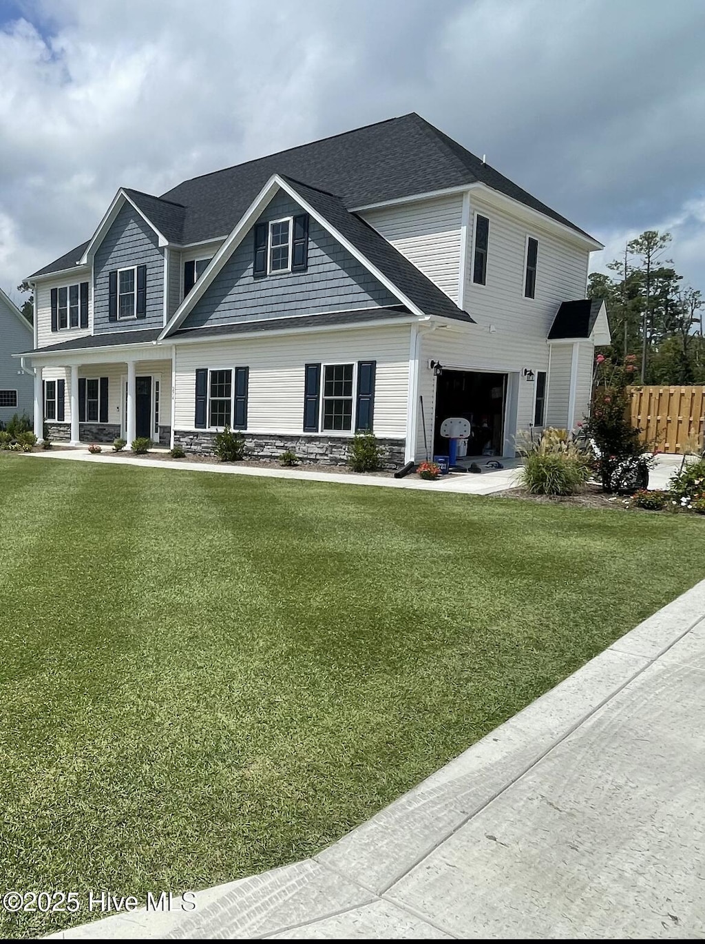 view of front of house with an attached garage, fence, a front yard, and stone siding