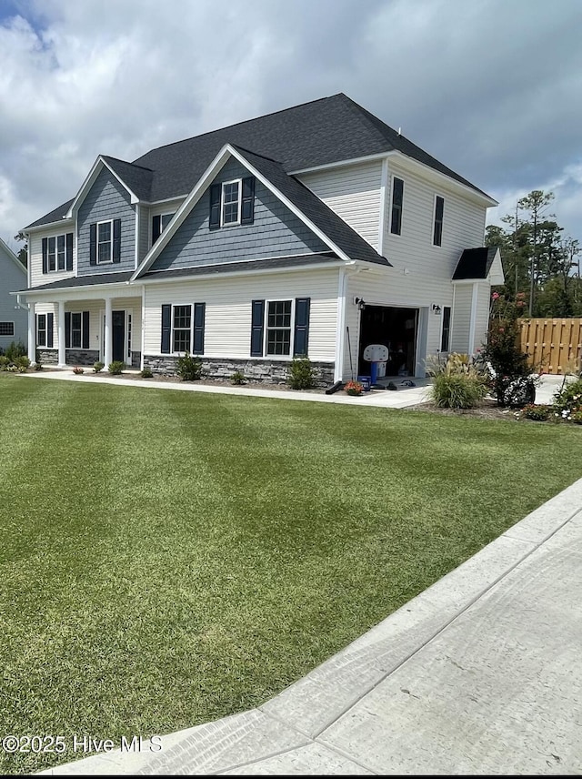 view of front of house with an attached garage, fence, a front yard, and stone siding