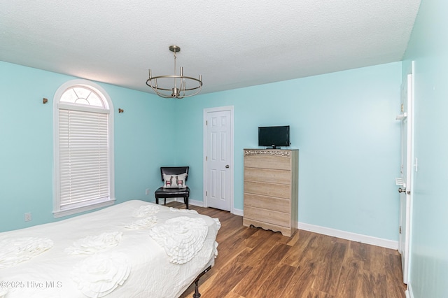 bedroom featuring baseboards, a textured ceiling, a chandelier, and dark wood-type flooring
