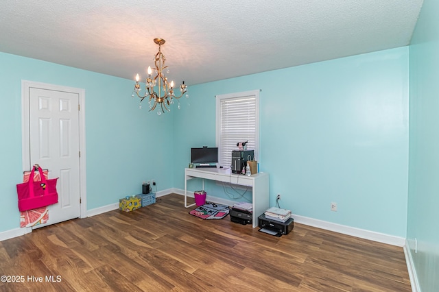 interior space with an inviting chandelier, a textured ceiling, baseboards, and wood finished floors