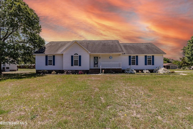 view of front of home featuring a shingled roof, a yard, and a porch