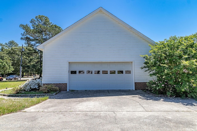 view of side of home featuring brick siding, an outbuilding, and a detached garage