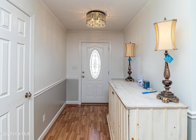 entryway featuring crown molding, baseboards, light wood finished floors, and a notable chandelier
