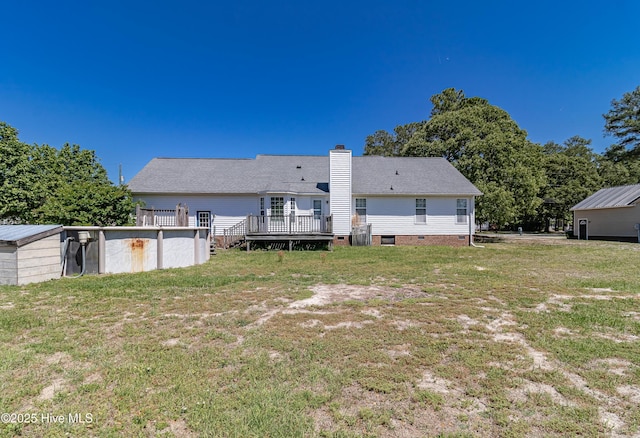 rear view of property with a lawn, a deck, crawl space, and a chimney
