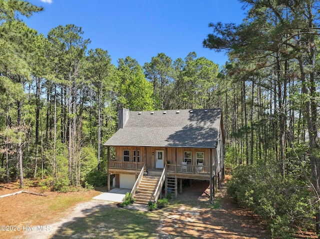 121 Pinewood Acres Dr, Powells Point, NC 27966 - rustic home with dirt driveway, stairs, a shingled roof, covered porch, and a garage