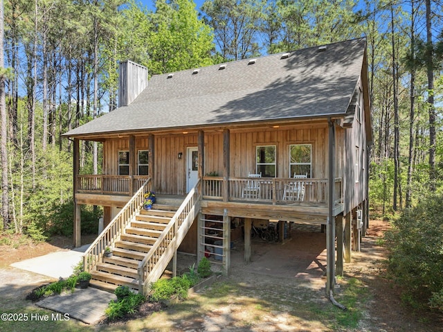 121 Pinewood Acres Dr, Powells Point, NC 27966 - view of front facade with stairway, a chimney, a carport, a shingled roof, and a porch