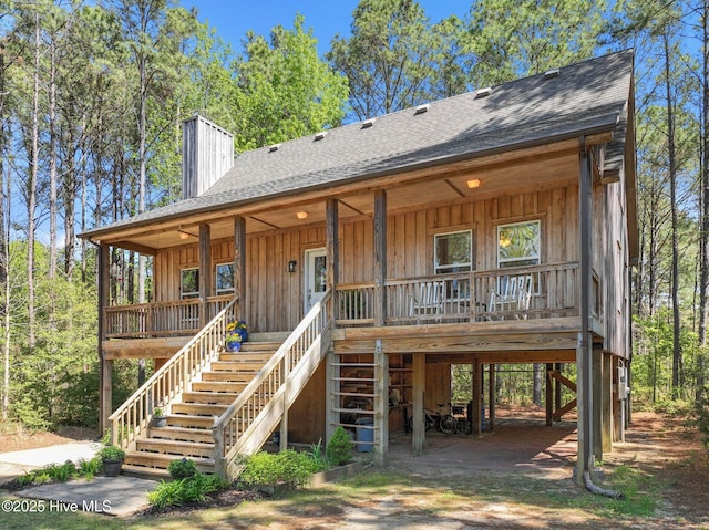 121 Pinewood Acres Dr, Powells Point, NC 27966 - view of front of house with stairway, a chimney, a shingled roof, covered porch, and a carport
