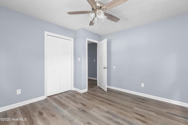 unfurnished bedroom featuring baseboards, a ceiling fan, a closet, and wood finished floors