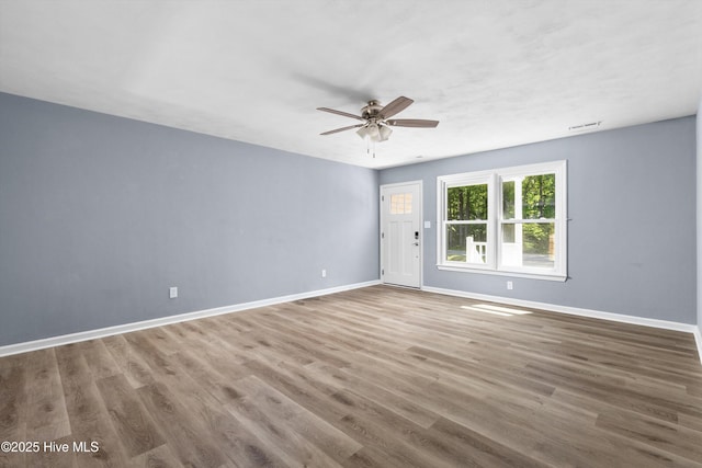 empty room with baseboards, ceiling fan, wood finished floors, and visible vents