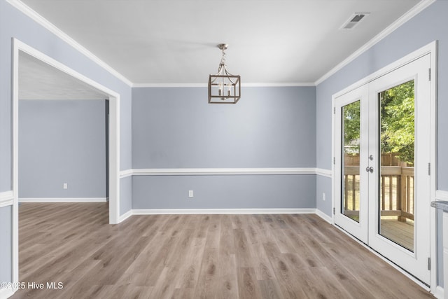 unfurnished dining area featuring crown molding, an inviting chandelier, french doors, and wood finished floors