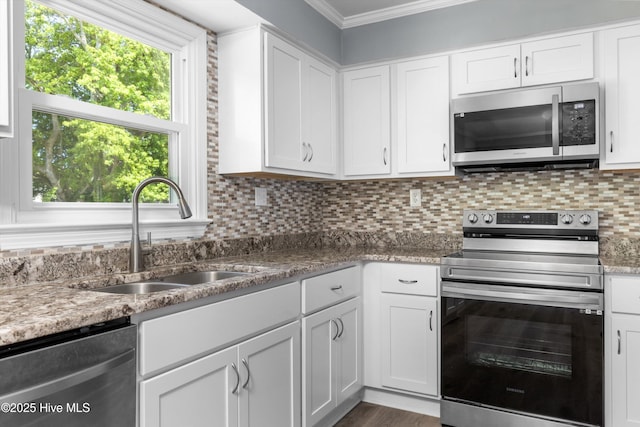 kitchen featuring crown molding, a sink, stainless steel appliances, white cabinetry, and tasteful backsplash