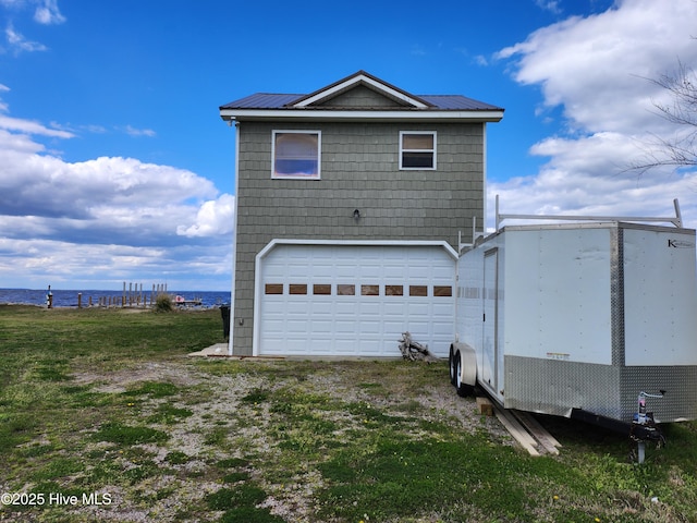 rear view of house with an attached garage, a water view, and metal roof