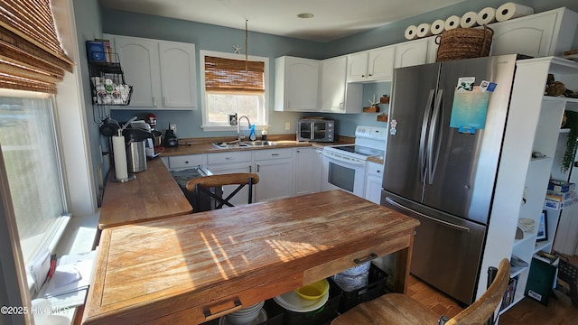 kitchen featuring freestanding refrigerator, white cabinetry, a sink, and white range with electric stovetop