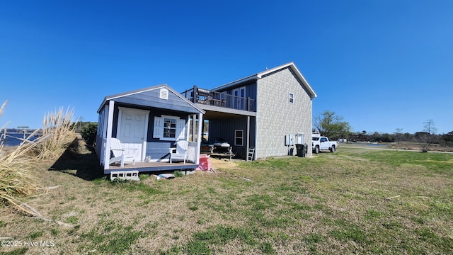 rear view of house featuring a wooden deck, a yard, and an outbuilding