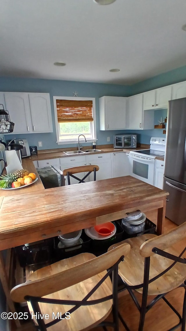 342 Owens Ln # 5, Columbia, NC 27925 - kitchen with white electric range, freestanding refrigerator, a sink, white cabinetry, and butcher block counters